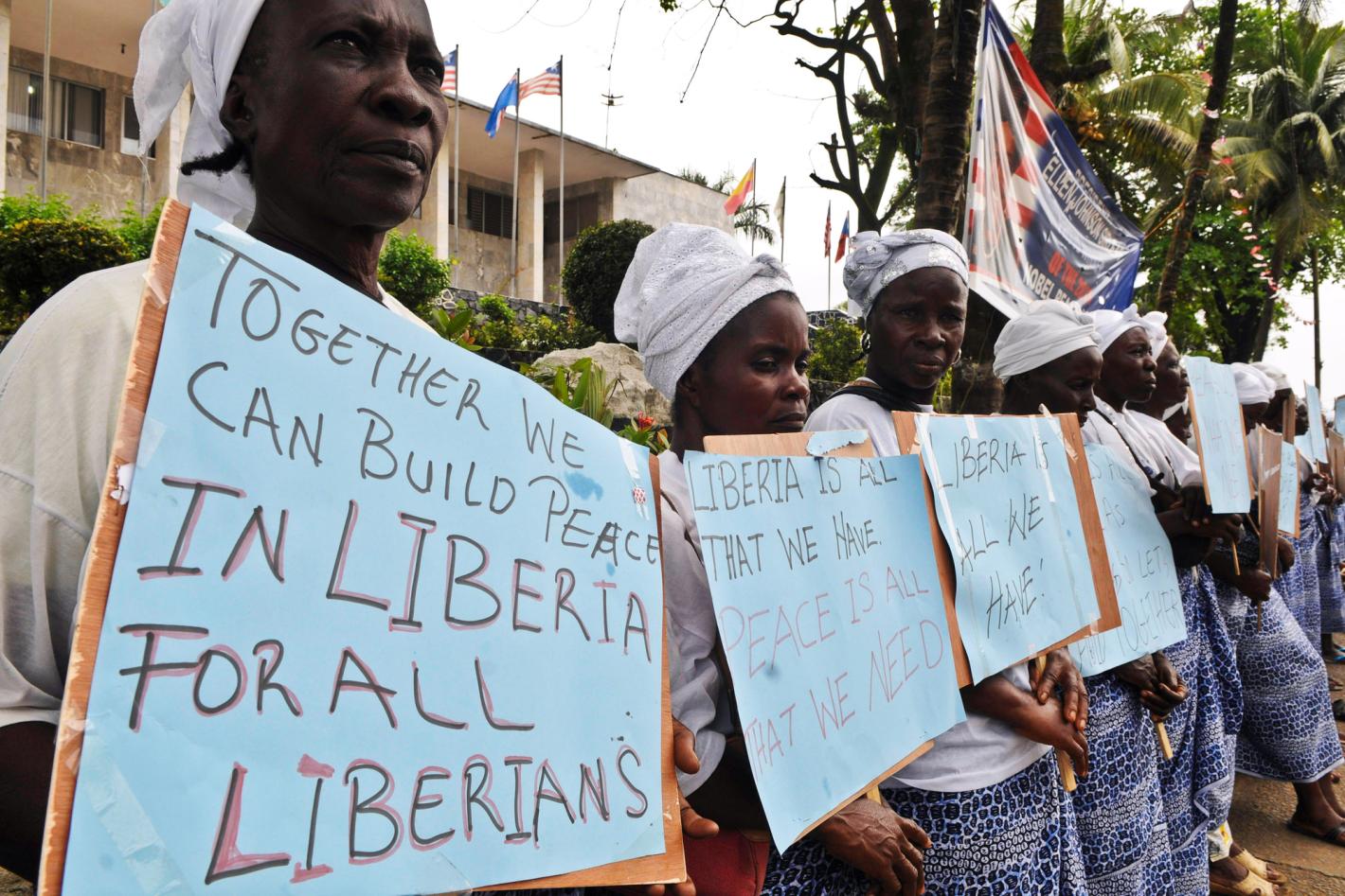 Women standing in a line holding hand written placards with messages for peace.